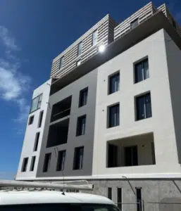 Ravalement de façade d'un immeuble à Lesneven, enduit blanc et gris avec balcons