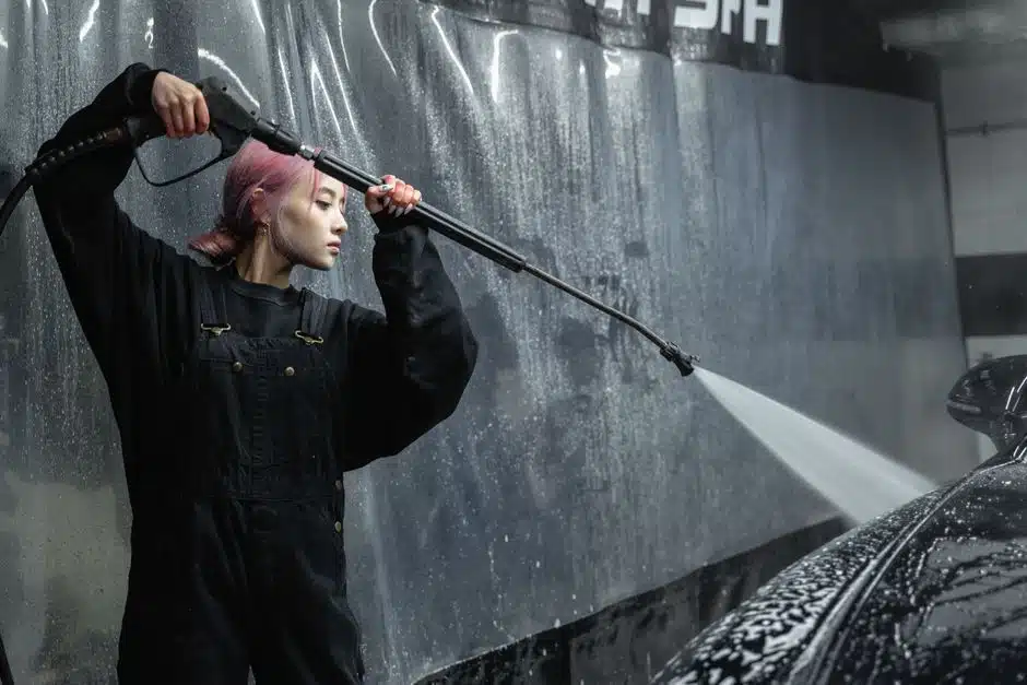 Femme tenant une lance haute pression devant un mur sombre