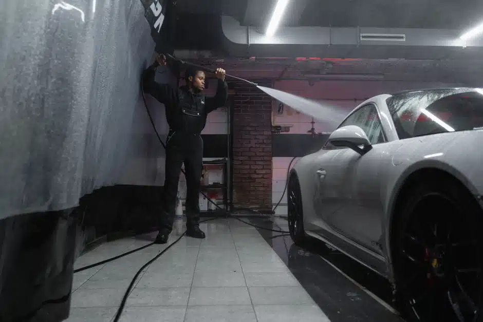 Homme nettoyant une voiture au jet haute pression dans un garage